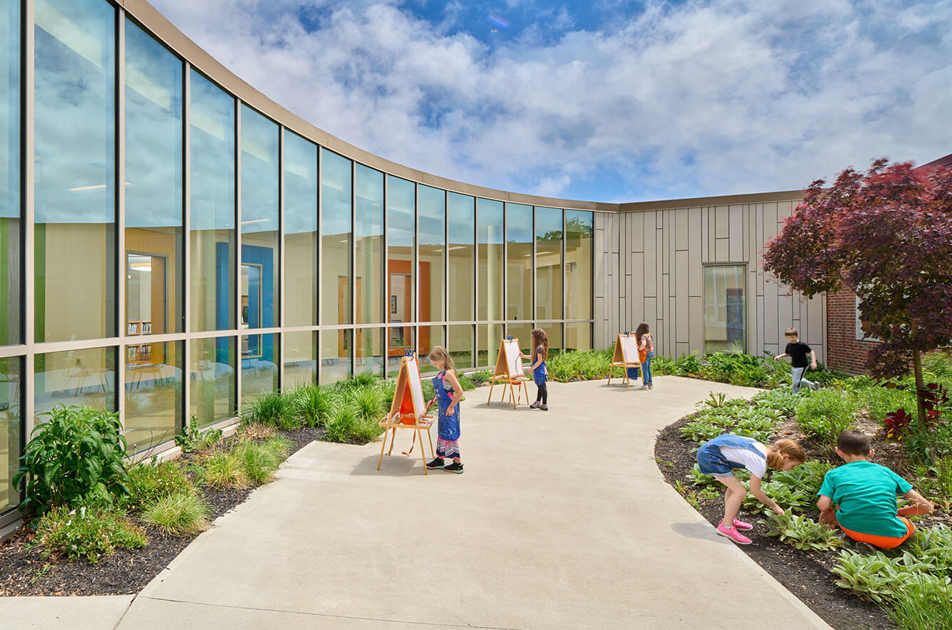 children playing outside in garden of elementary school designed by architects