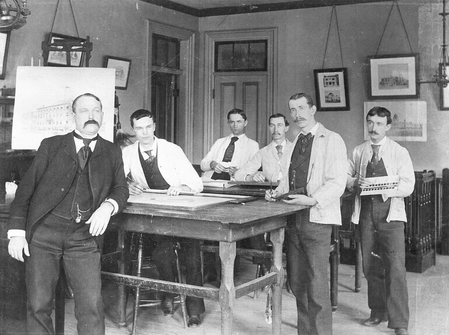 Old photograph of several male architects working around a table